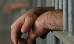 Hands behind jail bars